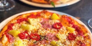 A close up photo of a pizza with a cheese and tomato topping
