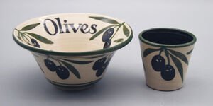 A photography of a large bowl decorated with the word 'olives' and illustrations of olives, and a small cup decorated with an illustration of an olive