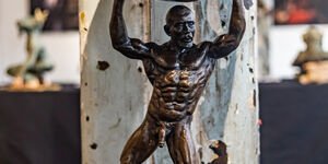 Image of a bronze statue of a man holding up a ball.