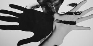 Abstract black and white photo of a face and hands.