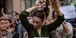 Image of a woman cutting her hair at a protest.