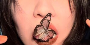 Photo of a woman holding a butterfly in her mouth.