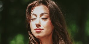 Image of a woman in a green dress standing in the sun.