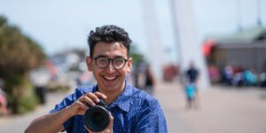 Image of a man smiling while holding a camera.