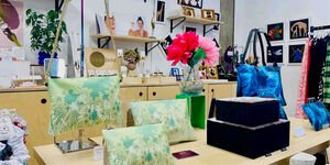 An interior of a shop with a table in the foreground, with purses and accessories displayed on it