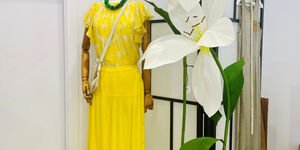 A long yellow dress is displayed on a mannequin