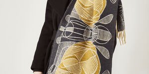 Image of a woman wearing a large navy and gold wool scarf.