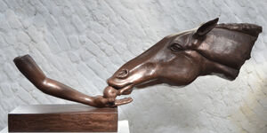An image of a sculpture. A horse is eating an apple out of a hand.