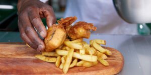 A wooden board wish 'fish' and chips laid on top