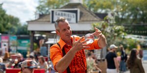 A main in an orange shirt holds a crystal ball between both hands