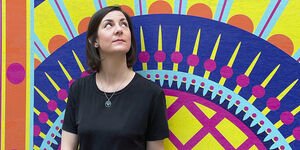 An image of Gina standing in front of her artwork at Bargehouse.