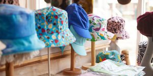 A selection of colourful hats are displayed on wooden stands