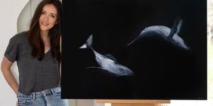 An image of Sophie Green standing next to her painting of humpback whales.