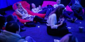 Image of a group of people sat in a room lit with blue lights.