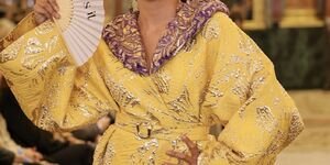 Image of a woman in a yellow dress holding a fan.