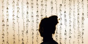 Silhouette of a woman in front of Chinese calligraphy.