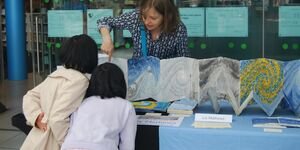 Image of Liz showing her work to two visitors.