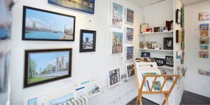 A white-walled gallery space filled with paintings and ceramics