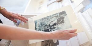 A person holds a print in their hands, only the arms and hands are visible 