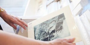 A photograph of a person's hands holding an artist print