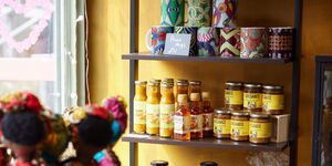 A selection of jars of sauces and colourful mugs on shelves, with a yellow wall behind