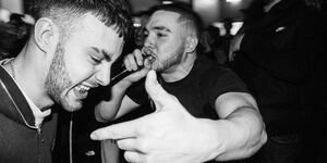 Two men in a crowd, one is performing