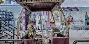 Image of a fair ground ride with soldiers sitting inside.