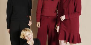 Image of three women stood together, two women are wearing red and one is wearing black.
