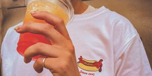 A woman drinking a slushie and modelling the shirt.