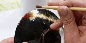 An image of someone painting brass powder on a Kintsugi ceramic.