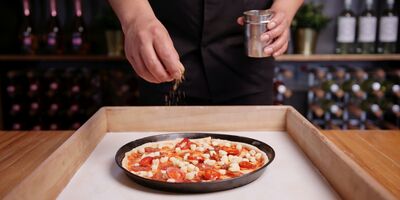 An image of someone making a pizza in the restaurant.