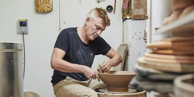 An image of Sotis creating a ceramic in his studio.
