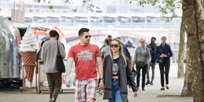 An image of two people walking along the riverside walkway.