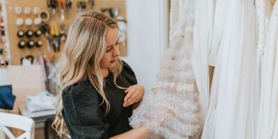 An image of Grace Lane London holding a dress in her studio.