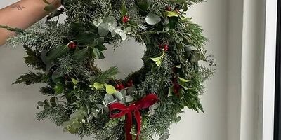 Image of a hand holding up a festive wreath.