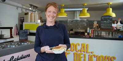 Image of Sonya holding a cheese toastie in her shop.
