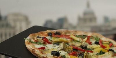 Image of a man holding up a pizza.