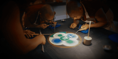 Image of two monks making art with sand.