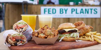 A selection of food on a wooden board, including a burger and chips.