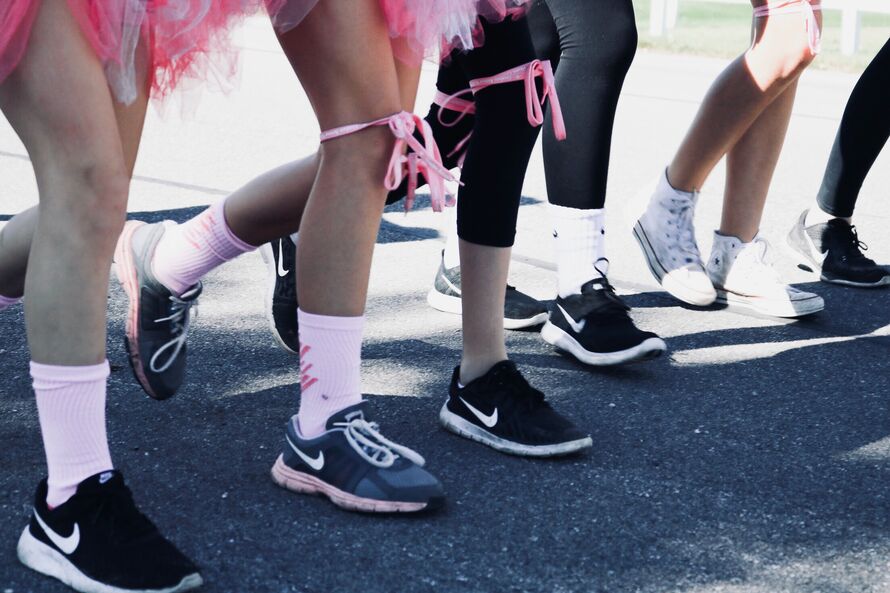 Image of people running with a pink ribbon tied to their legs.